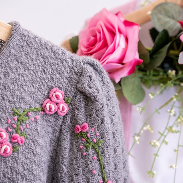 Grauer Trachtenstrick mit handgestickten rosa Blüten und Rosen aus der Sportalm Waltner in Nesselwang